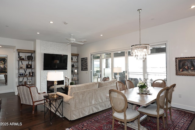 dining room featuring recessed lighting, dark wood finished floors, a fireplace, and ceiling fan with notable chandelier