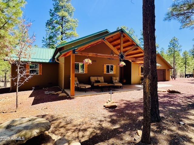 rear view of house with a patio, an outdoor living space, and metal roof