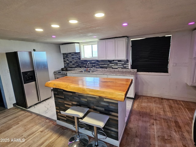 kitchen featuring sink, light hardwood / wood-style flooring, white cabinetry, stainless steel appliances, and decorative backsplash