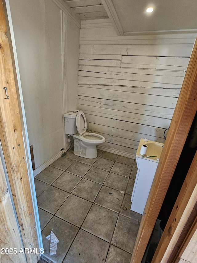 bathroom with tile patterned floors, wooden walls, and toilet