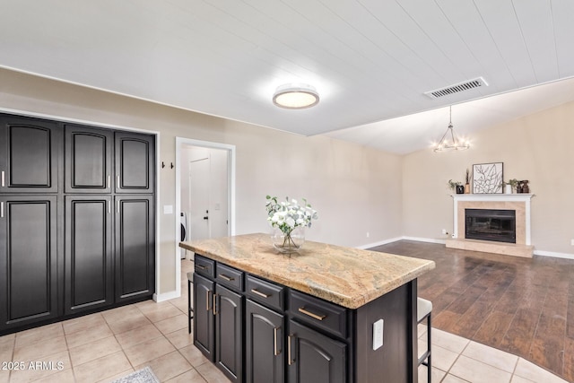 kitchen featuring washer / dryer, light stone counters, vaulted ceiling, a kitchen island, and pendant lighting