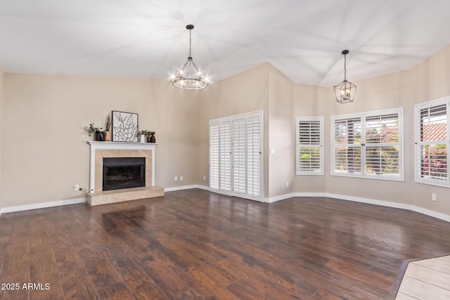 unfurnished living room featuring an inviting chandelier, lofted ceiling, and hardwood / wood-style floors