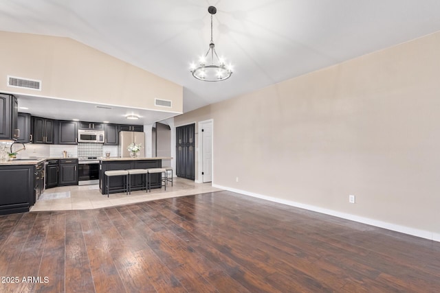 unfurnished living room featuring pendant lighting, sink, a kitchen island, a chandelier, and light wood-type flooring