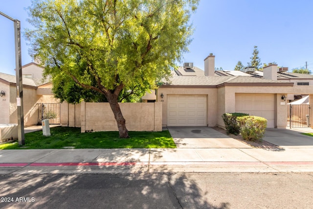 townhome / multi-family property with a garage, fence, stucco siding, a chimney, and driveway
