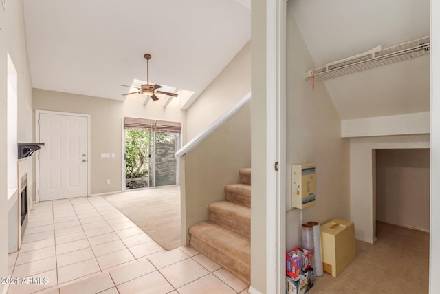 staircase featuring carpet floors, tile patterned floors, a ceiling fan, and lofted ceiling with skylight