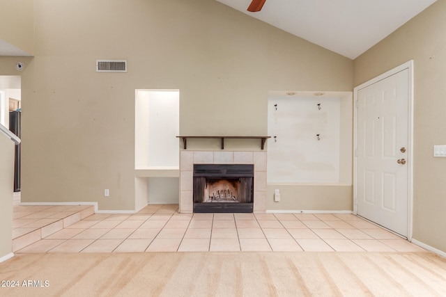 unfurnished living room featuring ceiling fan, high vaulted ceiling, a tile fireplace, and light colored carpet