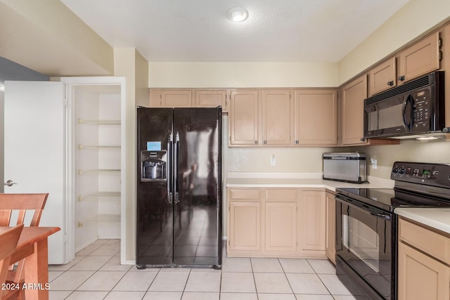 kitchen with light countertops, light tile patterned floors, and black appliances