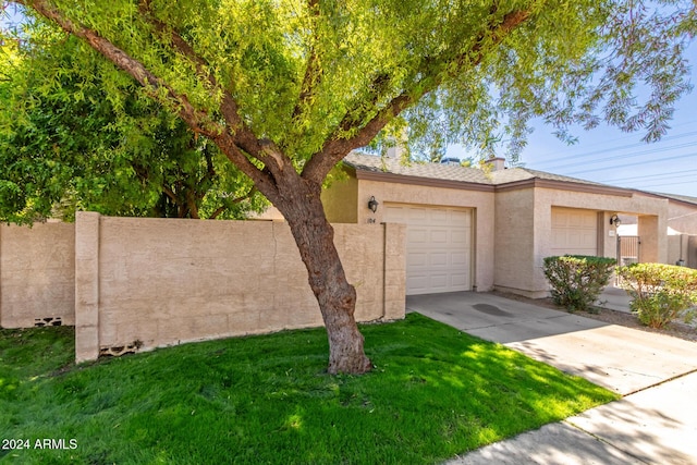 view of front facade with concrete driveway, an attached garage, a front yard, and stucco siding
