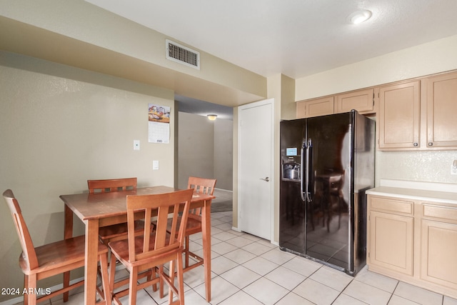 kitchen featuring light tile patterned floors, light brown cabinetry, and black refrigerator with ice dispenser