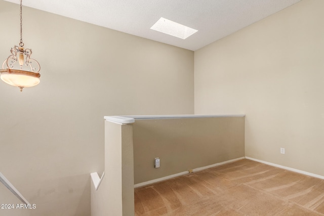 unfurnished room with a textured ceiling, carpet floors, and a skylight