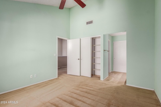 unfurnished bedroom with visible vents, carpet floors, baseboards, a closet, and a high ceiling