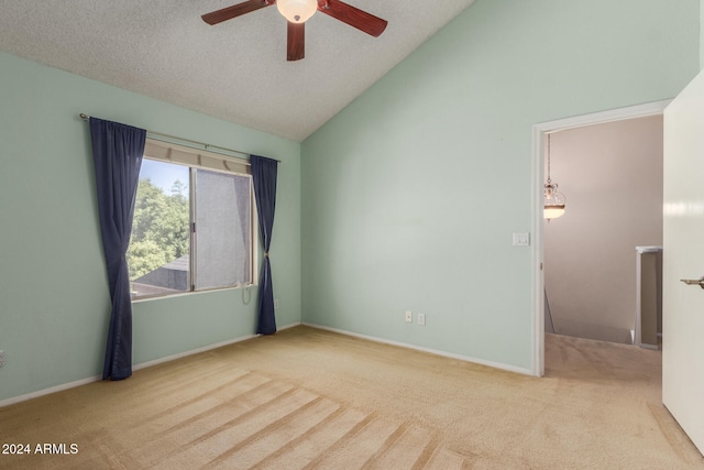 carpeted spare room featuring vaulted ceiling, a textured ceiling, and ceiling fan