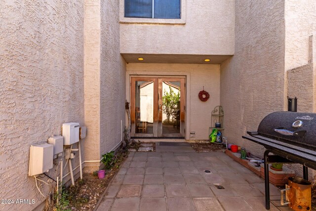 property entrance featuring a patio, french doors, and stucco siding