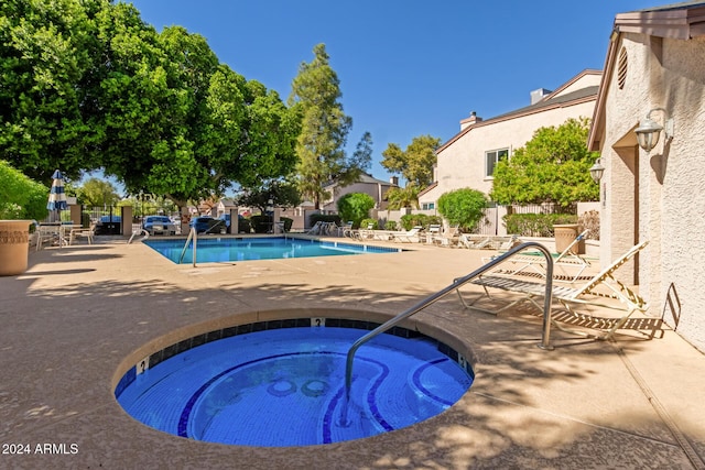 pool featuring a hot tub, a patio, and fence