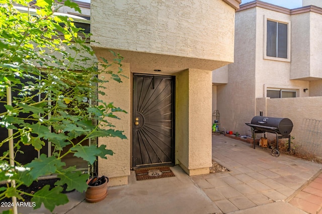 doorway to property featuring fence, stucco siding, and a patio area