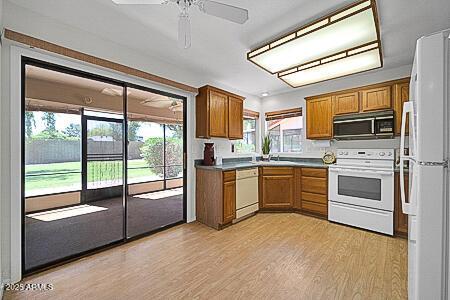 kitchen featuring white appliances, light wood-style floors, and brown cabinets