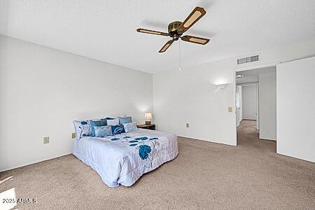 carpeted bedroom featuring ceiling fan and visible vents