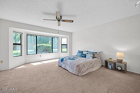 bedroom with a textured ceiling, a ceiling fan, and carpet