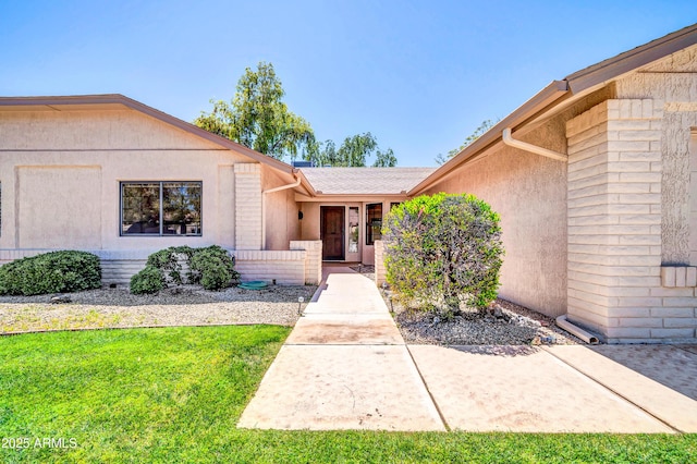 entrance to property with a yard and stucco siding