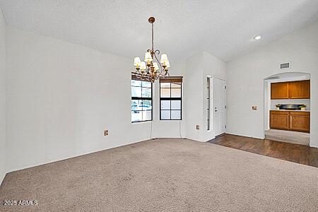 interior space with dark carpet, recessed lighting, arched walkways, and a chandelier