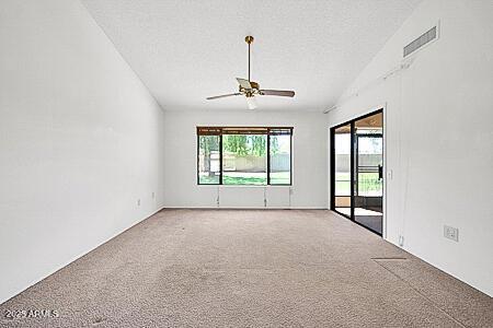 unfurnished room with a textured ceiling, ceiling fan, carpet, and visible vents
