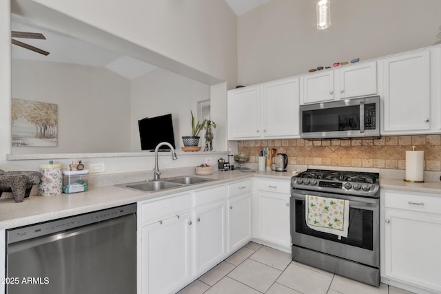 kitchen with a sink, appliances with stainless steel finishes, white cabinetry, vaulted ceiling, and decorative backsplash