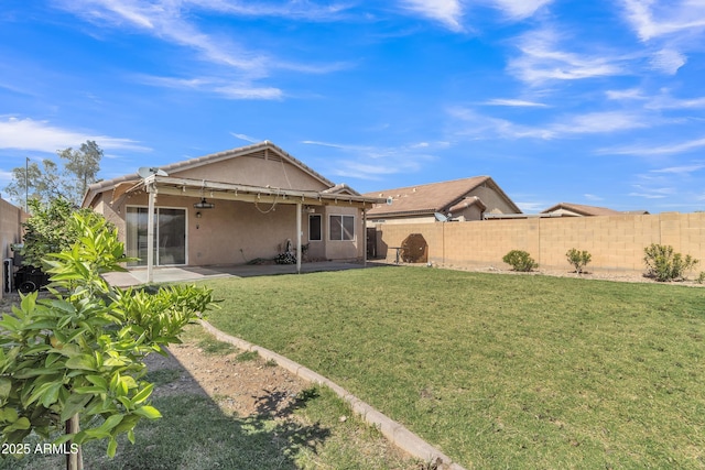 rear view of house with a patio, stucco siding, a fenced backyard, a tiled roof, and a lawn
