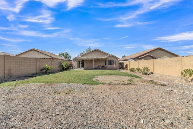 rear view of property featuring a yard, a fenced backyard, and a patio area