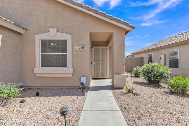 doorway to property featuring fence and stucco siding