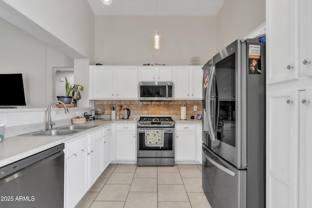 kitchen featuring light tile patterned floors, backsplash, white cabinets, appliances with stainless steel finishes, and a sink