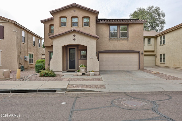 mediterranean / spanish house featuring stucco siding, a garage, concrete driveway, and a tile roof