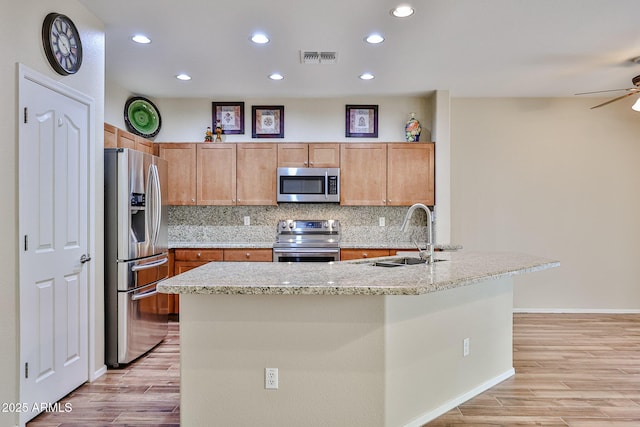 kitchen with tasteful backsplash, stainless steel appliances, light wood-style floors, and a sink