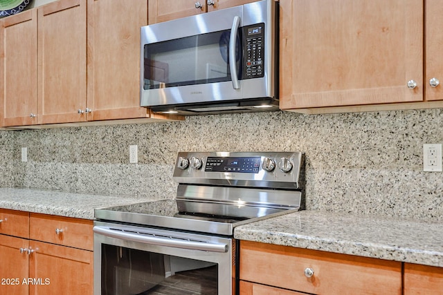 kitchen featuring light stone counters, decorative backsplash, stainless steel appliances, and light brown cabinetry