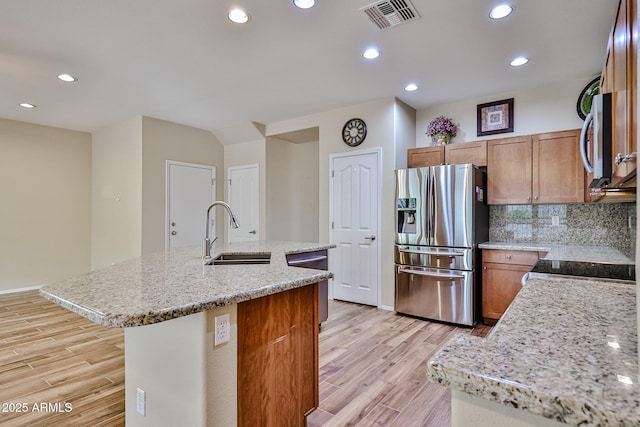 kitchen featuring visible vents, a center island with sink, light wood-style flooring, a sink, and stainless steel appliances