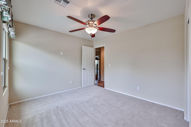 carpeted spare room featuring visible vents, ceiling fan, and baseboards