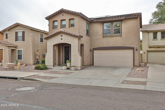 mediterranean / spanish-style home featuring stucco siding, concrete driveway, a garage, a tiled roof, and roof mounted solar panels