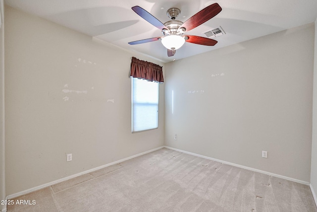 unfurnished room with visible vents, baseboards, light colored carpet, and a ceiling fan