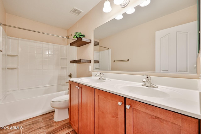 full bath with toilet, wood finished floors, visible vents, and a sink