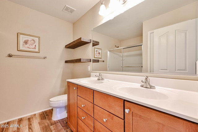 bathroom with a sink, visible vents, wood finished floors, and a shower stall