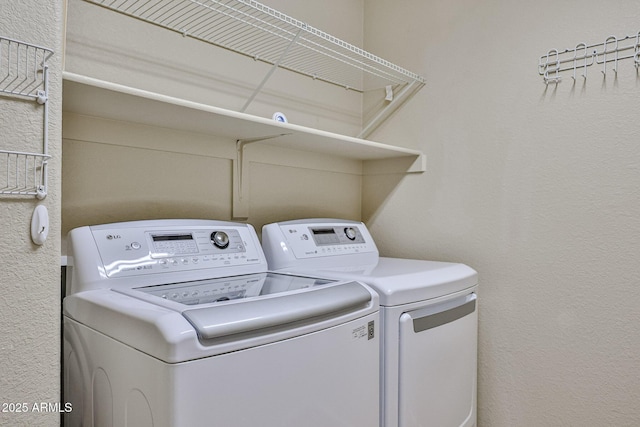 laundry room with laundry area, washing machine and dryer, and a textured wall