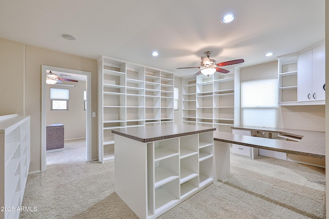 walk in closet with light carpet and ceiling fan