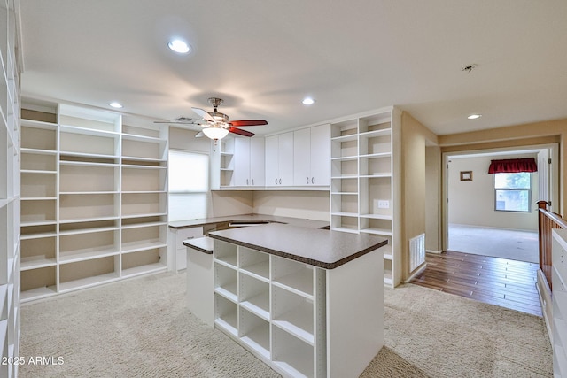 spacious closet featuring visible vents, light carpet, and a ceiling fan