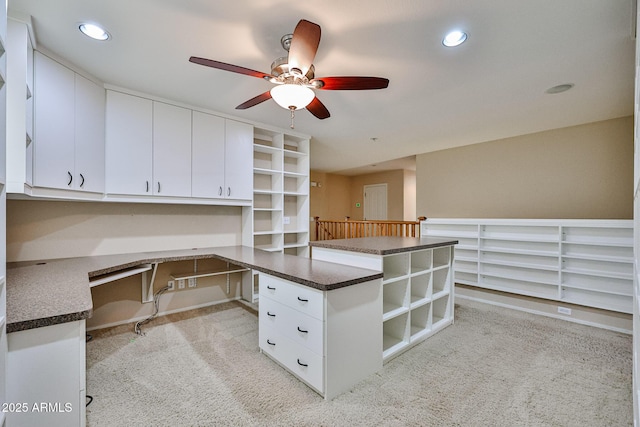 interior space with dark countertops, light carpet, built in desk, recessed lighting, and a peninsula