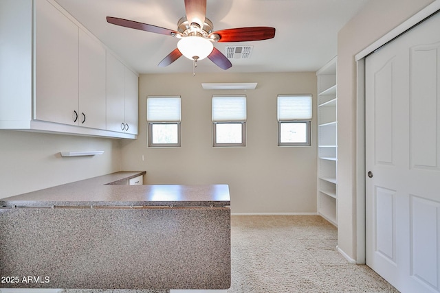 kitchen with visible vents, baseboards, a peninsula, white cabinetry, and a ceiling fan