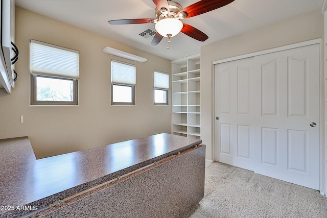 unfurnished office with visible vents, carpet flooring, and a ceiling fan