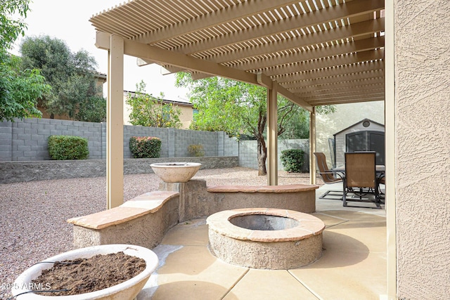 view of patio / terrace featuring an outdoor structure, a fenced backyard, a pergola, and an outdoor fire pit