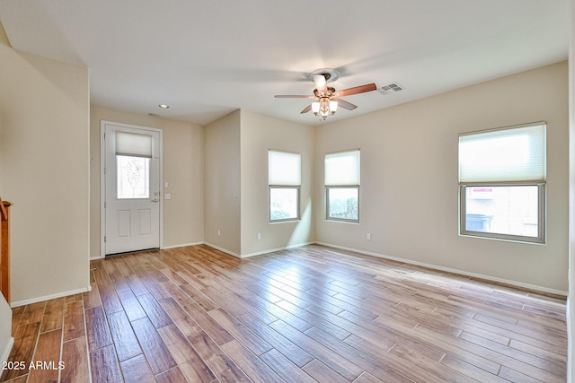 unfurnished room featuring baseboards, visible vents, light wood finished floors, and ceiling fan