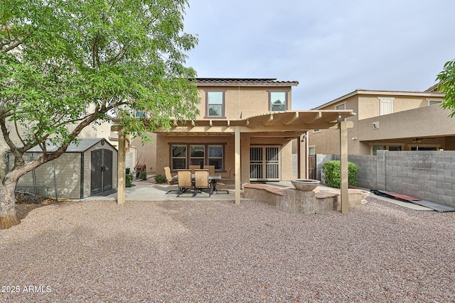 rear view of house with solar panels, fence, a storage shed, an outdoor structure, and a patio area