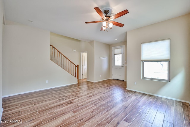 interior space with ceiling fan, stairway, baseboards, and wood finished floors