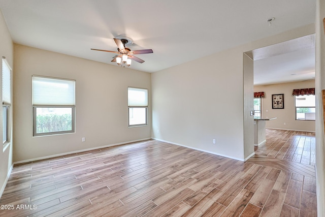 unfurnished room featuring baseboards, light wood-style flooring, and a ceiling fan